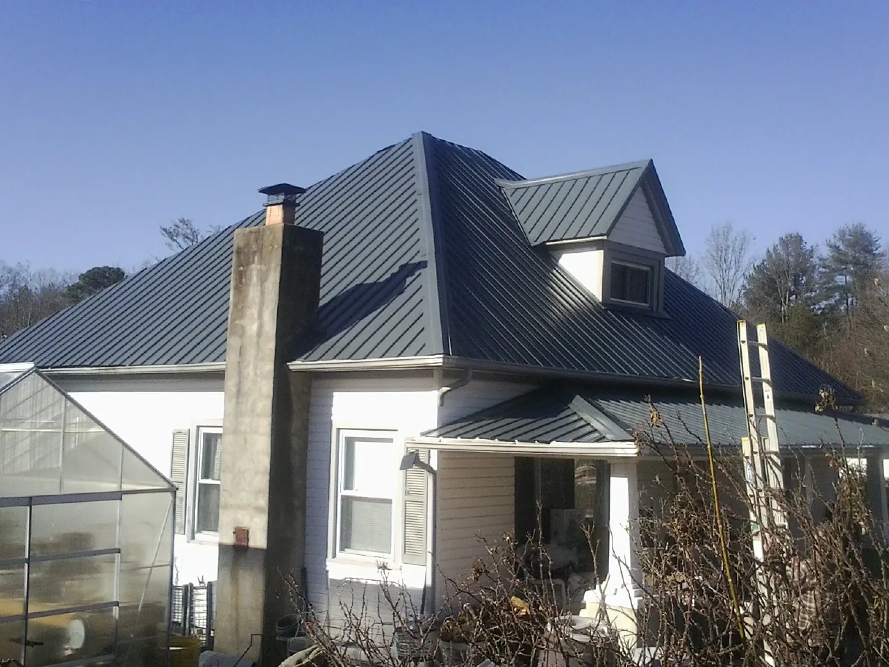 Dark blue standing seam metal roof on a white farmhouse with dormer — Slate & Tile Roof Repair by Roofing Brothers in Wind Gap