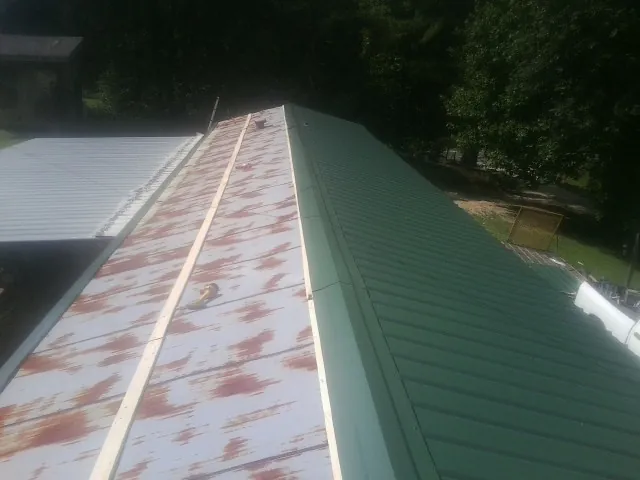 Old rusted panels beside newly installed green metal roofing — Wind Damage Roof Repair by Roofing Brothers in Wind Gap