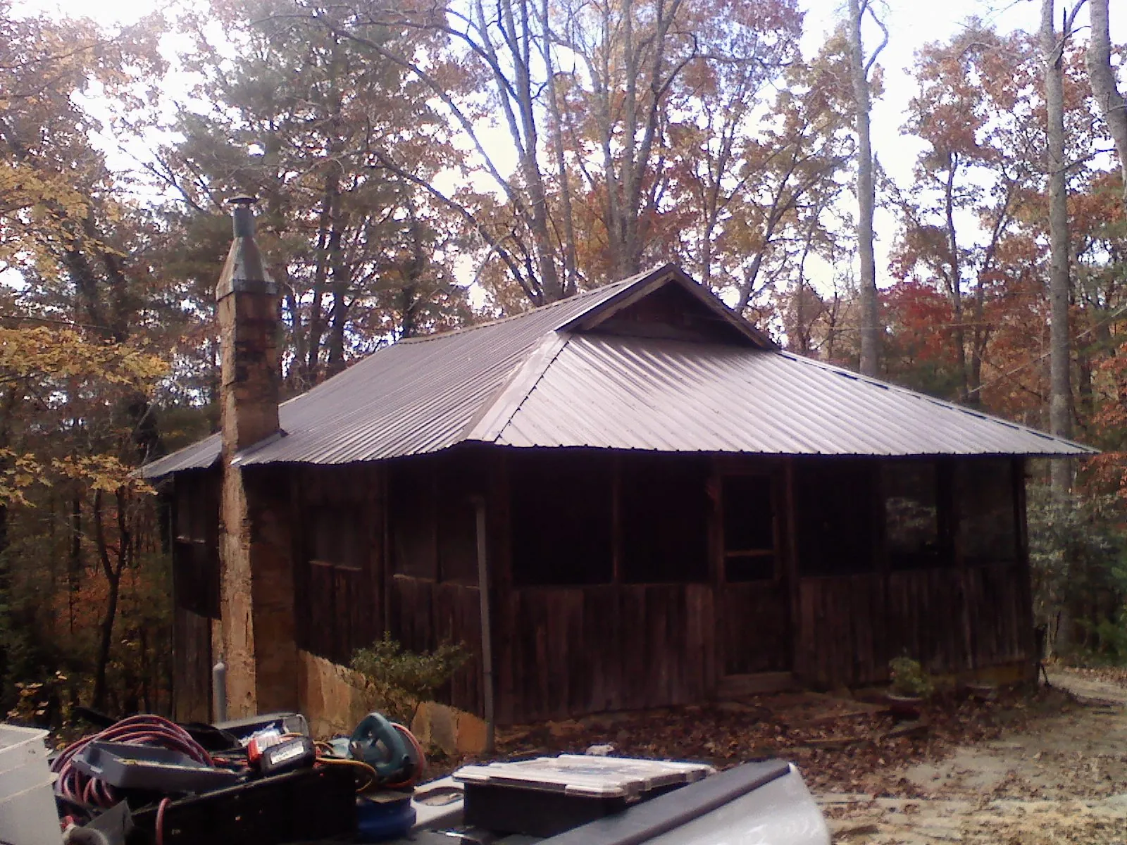 Brown metal hip roof on an old cabin with a stone chimney in Wind Gap